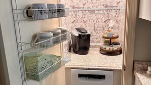 Une cuisine compacte équipée d’un lave-vaisselle, de rangements pour les ustensiles de cuisine et d’un mur décoratif.