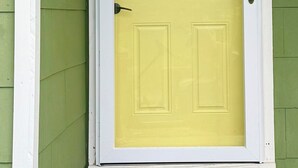 Une porte jaune avec un cadre blanc, un panneau de verre et une poignée de porte.
