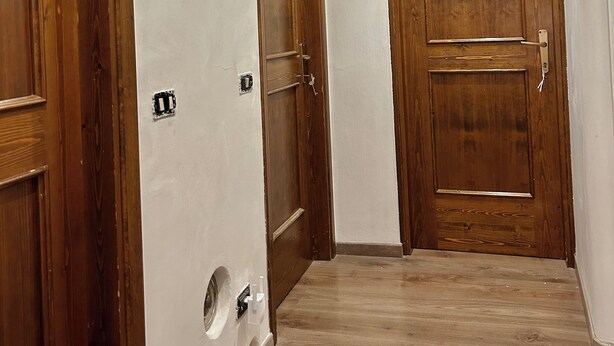 Un pasillo con puertas de madera y una pared blanca.