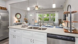 Una cocina moderna con armarios blancos, electrodomésticos de acero inoxidable e iluminación colgante.