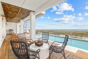 A covered outdoor area with a pool, wicker chairs, and a view of the ocean. - Infinity: Gorgeous Beachfront Home, Private Pool, Pet Friendly, Amazing Views, M (Mexico Beach)