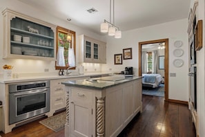A kitchen with a central island, built-in oven, and white cabinetry.