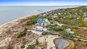 An aerial view of a coastal residential area with houses, a beach, and a clear view of the ocean. - Magnolia by the Sea: Beachfront Home, Private Pool, Mother-In-Law, Secluded Beac (Indian Pass)