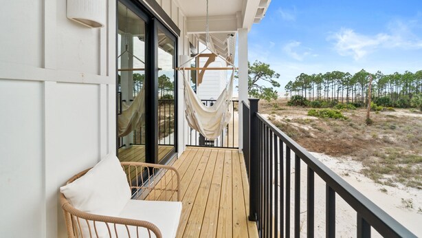 A wooden deck with a hammock, a wicker chair, and a table. - Magnolia by the Sea: Beachfront Home, Private Pool, Mother-In-Law, Secluded Beac (Indian Pass)