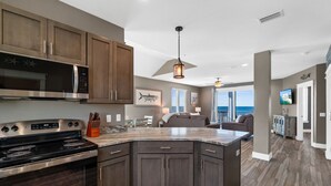 A modern kitchen with dark wood cabinets, stainless steel appliances, and a large island. - Beachfront Duplex Unit, Pet Friendly, Mexico Beach, Gorgeous Views! (Mexico Beach)