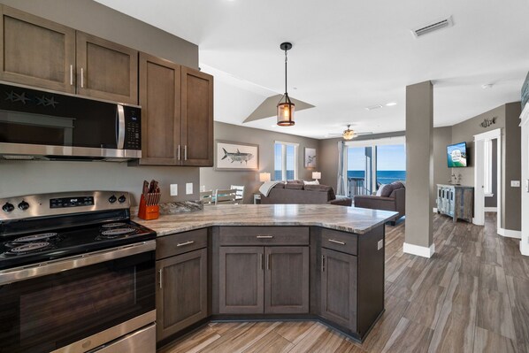 A modern kitchen with dark wood cabinets, stainless steel appliances, and a large island.