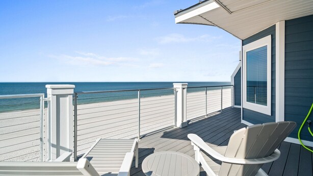 A wooden deck with a view of the beach, a chair, and a small table. - Beachfront Duplex Unit, Pet Friendly, Mexico Beach, Gorgeous Views! (Mexico Beach)