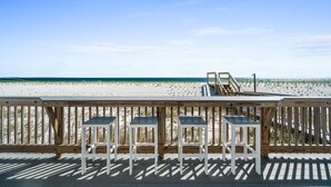 A wooden deck with three white chairs and a wooden staircase leading to a beach. - Beachfront Duplex Unit, Pet Friendly, Mexico Beach, Gorgeous Views! (Mexico Beach)