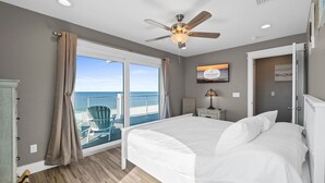 A bedroom with a large bed, a ceiling fan, a view of the ocean, and a sign on the wall. - Beachfront Duplex Unit, Pet Friendly, Mexico Beach, Gorgeous Views! (Mexico Beach)