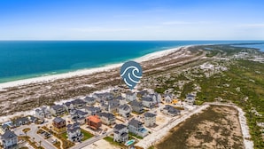 A coastal residential area with houses, a beach, and a clear view of the ocean. - Estate Home: Gulf Views, Private Pool, Pool Table, Sleeps 20! (Mexico Beach)
