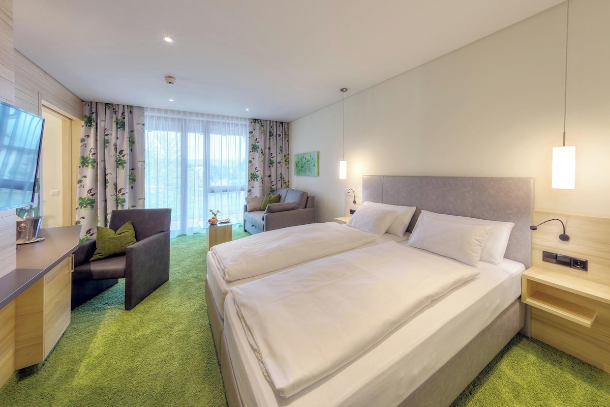 Ein Hotelzimmer mit einem großen Bett, einem Schreibtisch, einem Sessel und einer Couch.