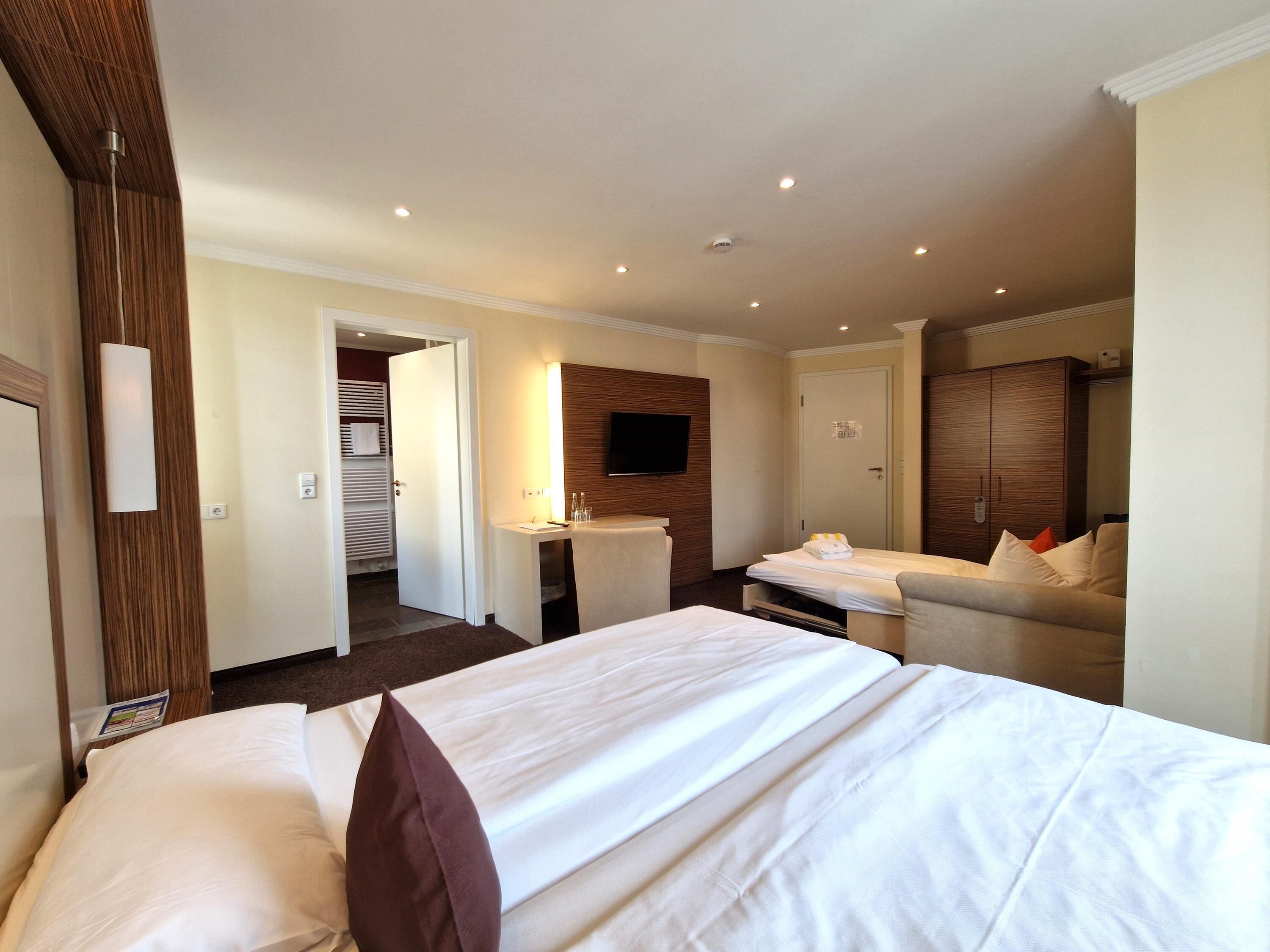 Une chambre d’hôtel comprenant un lit, un petit bureau, un coin salon et un téléviseur.