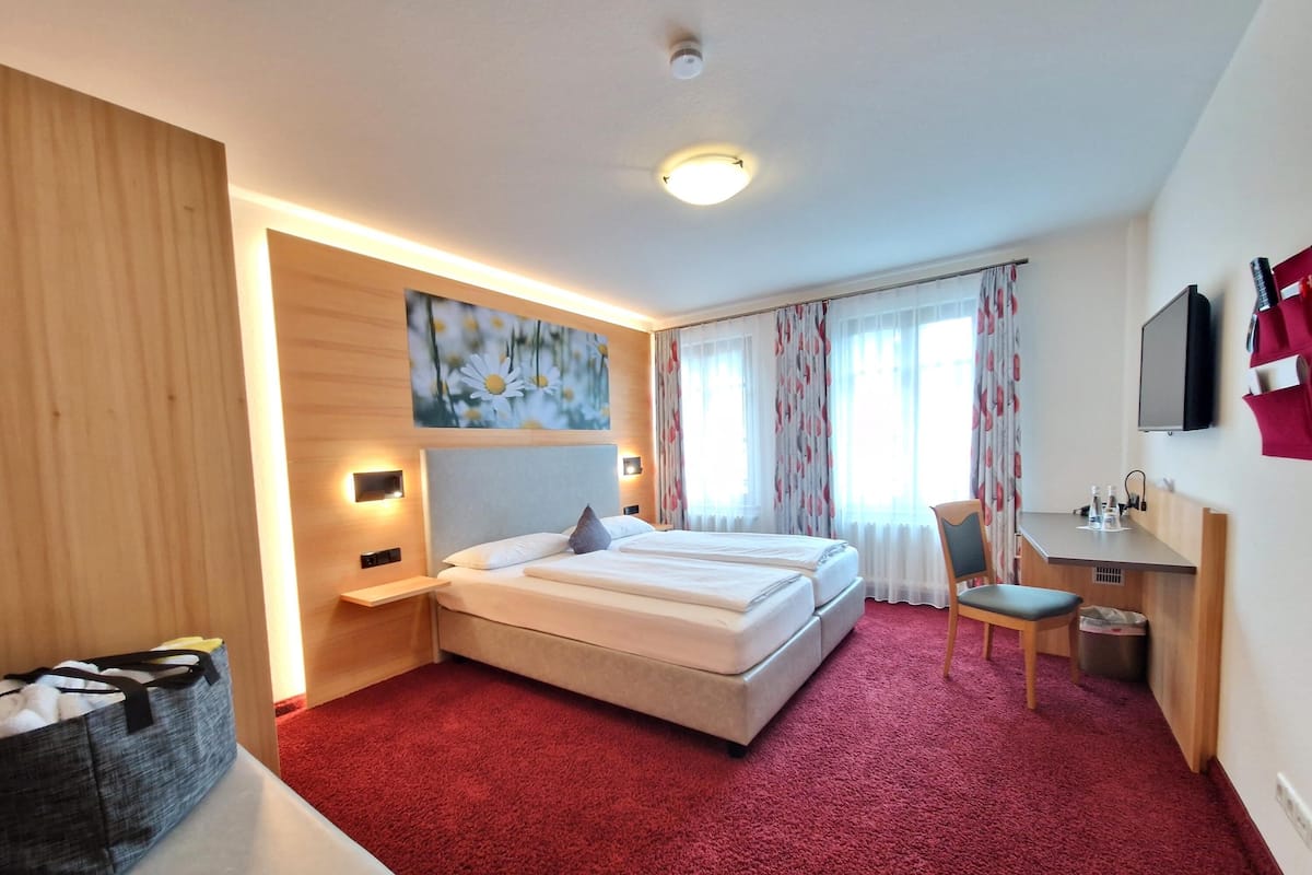 Ein Hotelzimmer mit einem großen Bett, einem Schreibtisch, einem Stuhl und einem Fernseher.