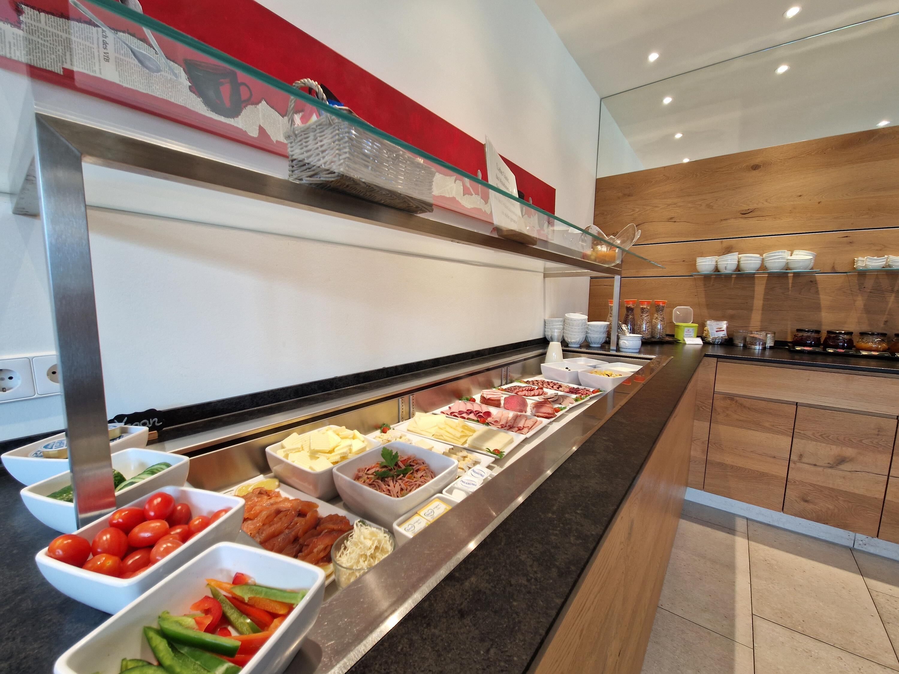 A buffet with various food items including meats, cheeses, and vegetables.