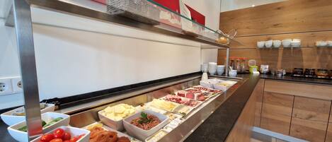 A buffet with various food items including meats, cheeses, and vegetables.