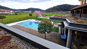A modern outdoor pool area with a view of vineyards and hills in the background. - Mosers Blume Relax & Genuss Hotel (Haslach im Kinzigtal)