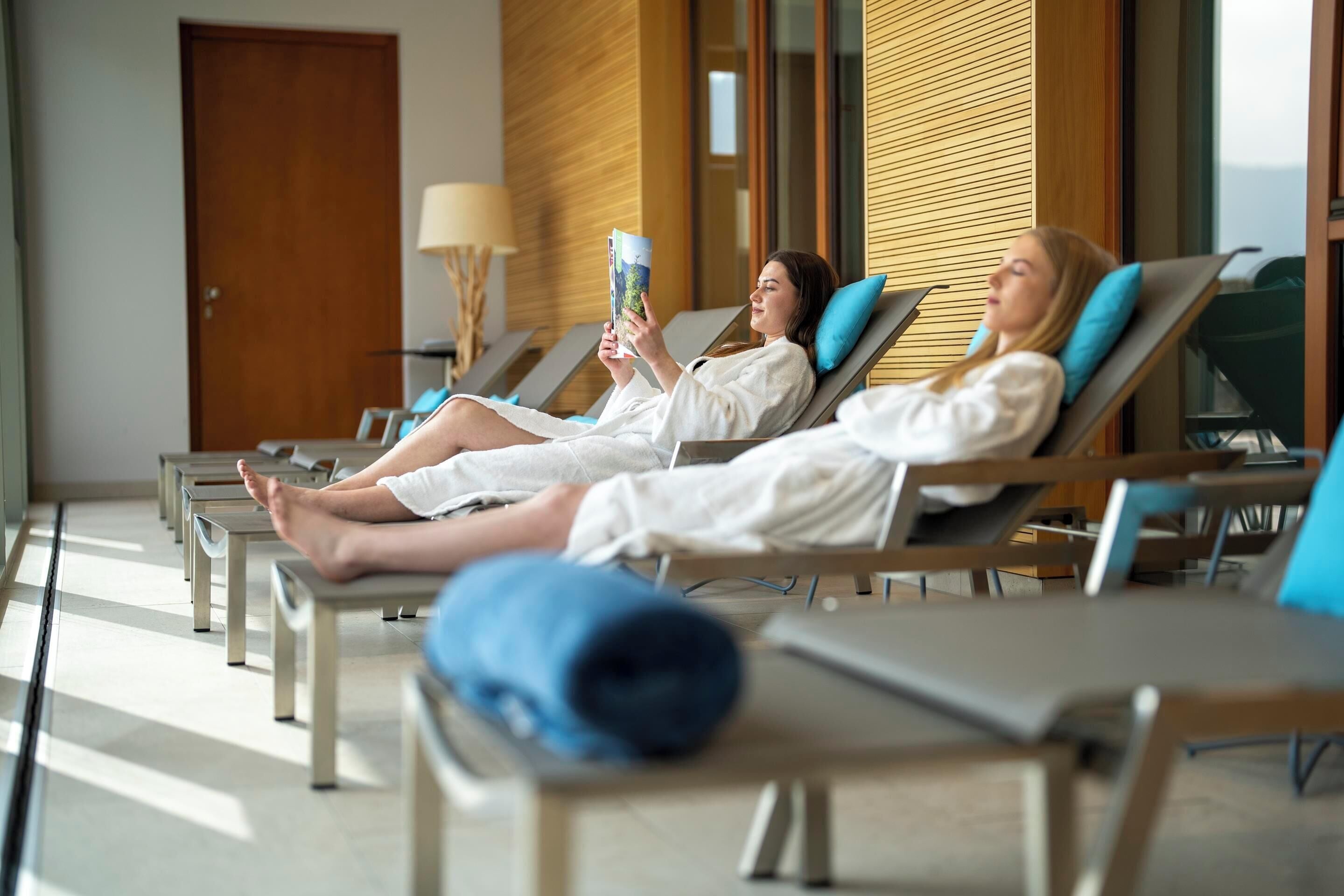 A modern spa area with reclining chairs, a wooden wall, and a door in the background.