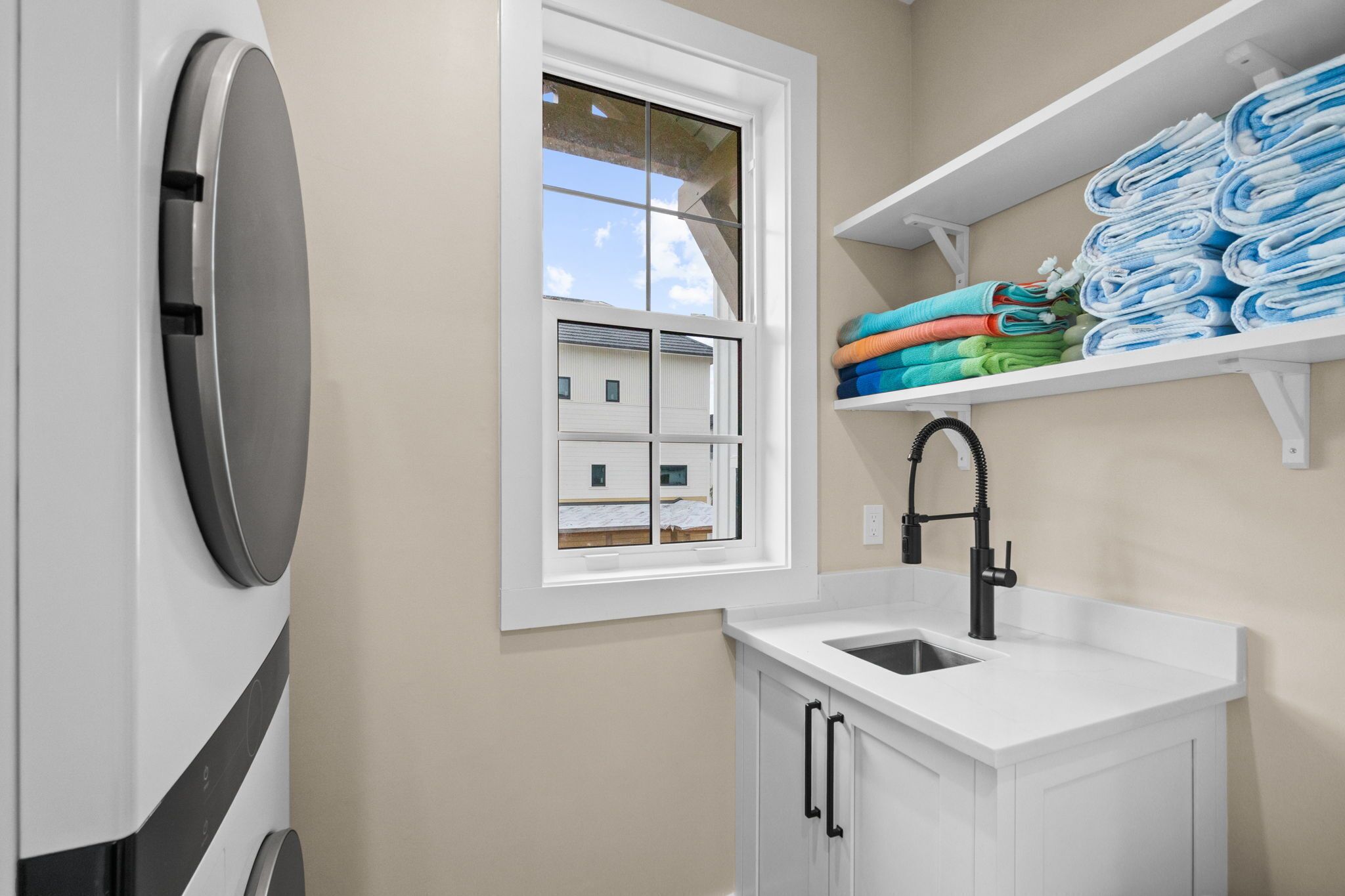 A laundry room with a washing machine, a sink, and a window.