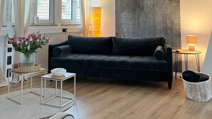 A modern living room with a dark sofa, a large abstract painting, and a wooden floor. - Vacation apartment with wellness - in the heart of Worms! (Worms)