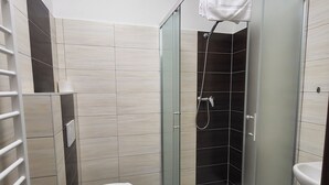 Une salle de bain moderne dotée d’une douche à parois de verre, de toilettes et d’un lavabo.