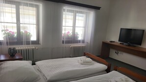 Une chambre d’hôtel avec deux lits, une télévision et une vue sur l’extérieur grâce à de grandes fenêtres.