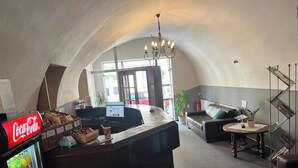 Un espace d’accueil comprenant un réfrigérateur Coca-Cola, un ordinateur et un coin salon avec un canapé et une petite table.