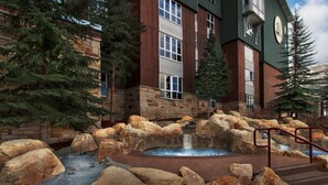 Un hôtel doté d’une façade en pierre, d’un bain à remous et d’une cascade décorative.