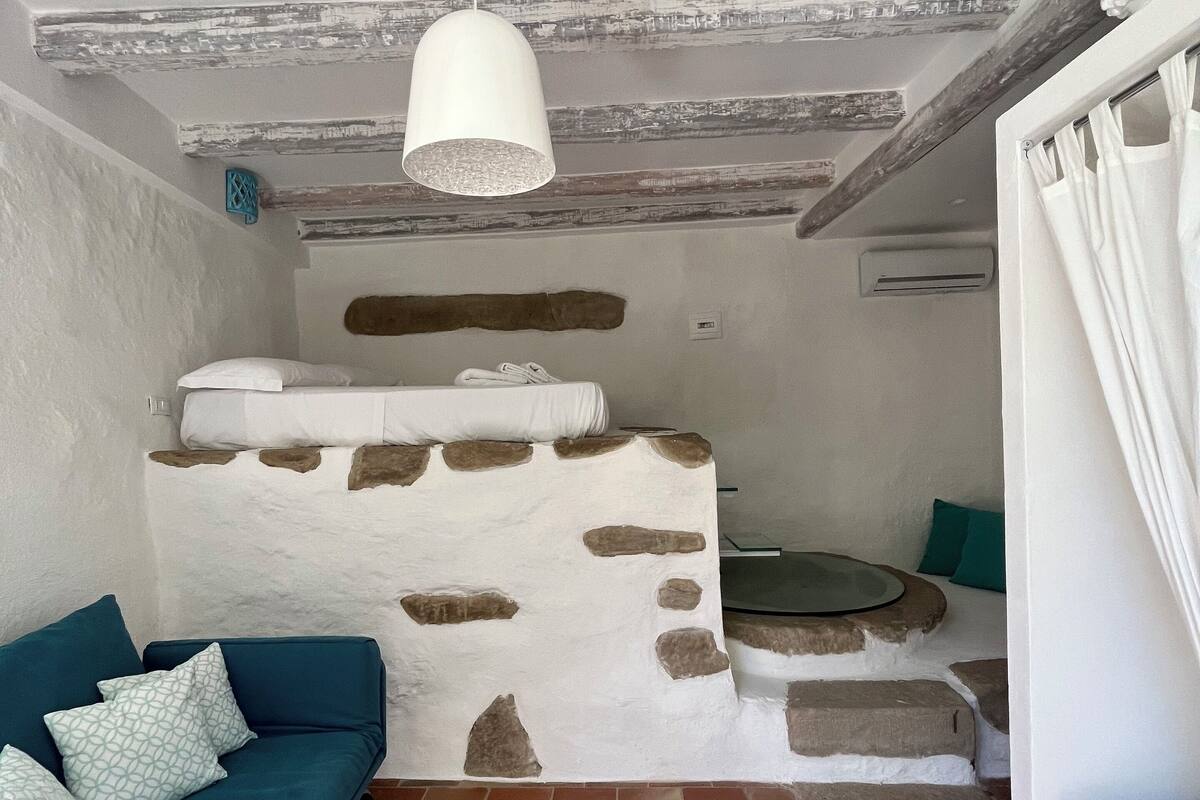 A rustic room with a blue sofa, a stone wall, and a hanging light fixture.