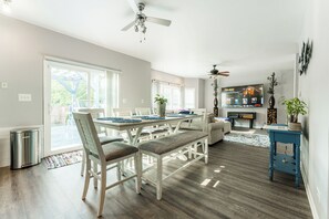 A modern kitchen with a dining area, wooden flooring, and a ceiling fan.