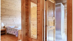 A wooden room with a bed, a nightstand, and a door leading to another room. - Comfortable Home With Terrace (Masserberg)