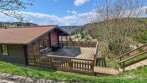 A wooden cabin with a deck, surrounded by a wooden fence, overlooking a valley. - Comfortable Home With Terrace (Masserberg)