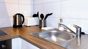 Une cuisine moderne équipée d’un évier en acier inoxydable, d’une bouilloire, d’un grille-pain et d’un porte-ustensiles.