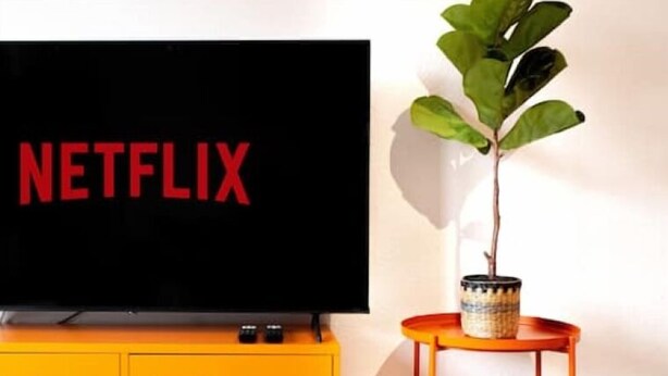 Un téléviseur dont l’écran affiche le mot « NETFLIX », posé sur un meuble jaune.