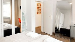 Une chambre à coucher moderne, avec un lit, un miroir et une porte donnant sur une autre pièce.