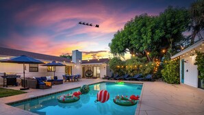 A swimming pool with inflatable toys, outdoor seating, and string lights.