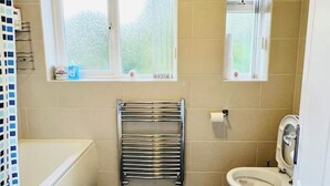 Un baño pequeño con bañera, inodoro y un perchero para toallas.