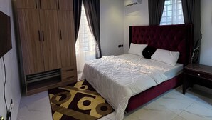Quarto moderno com cama grande, roupeiro embutido e iluminação azul no teto.