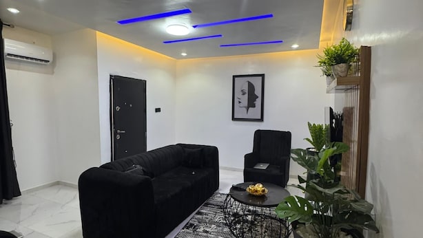 Uma sala de estar moderna com um sofá preto, uma mesa de centro e um vaso de planta.