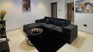 Uma sala de estar moderna com um sofá modular, uma mesa de centro e um quadro na parede.