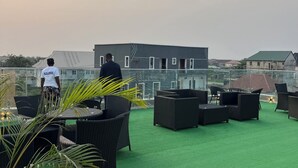 Terraço no telhado com área de estar ao ar livre e vista para prédios ao fundo.