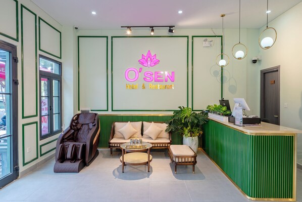 A reception area with a green reception desk, a massage chair, a sofa, and a small table with a tray.