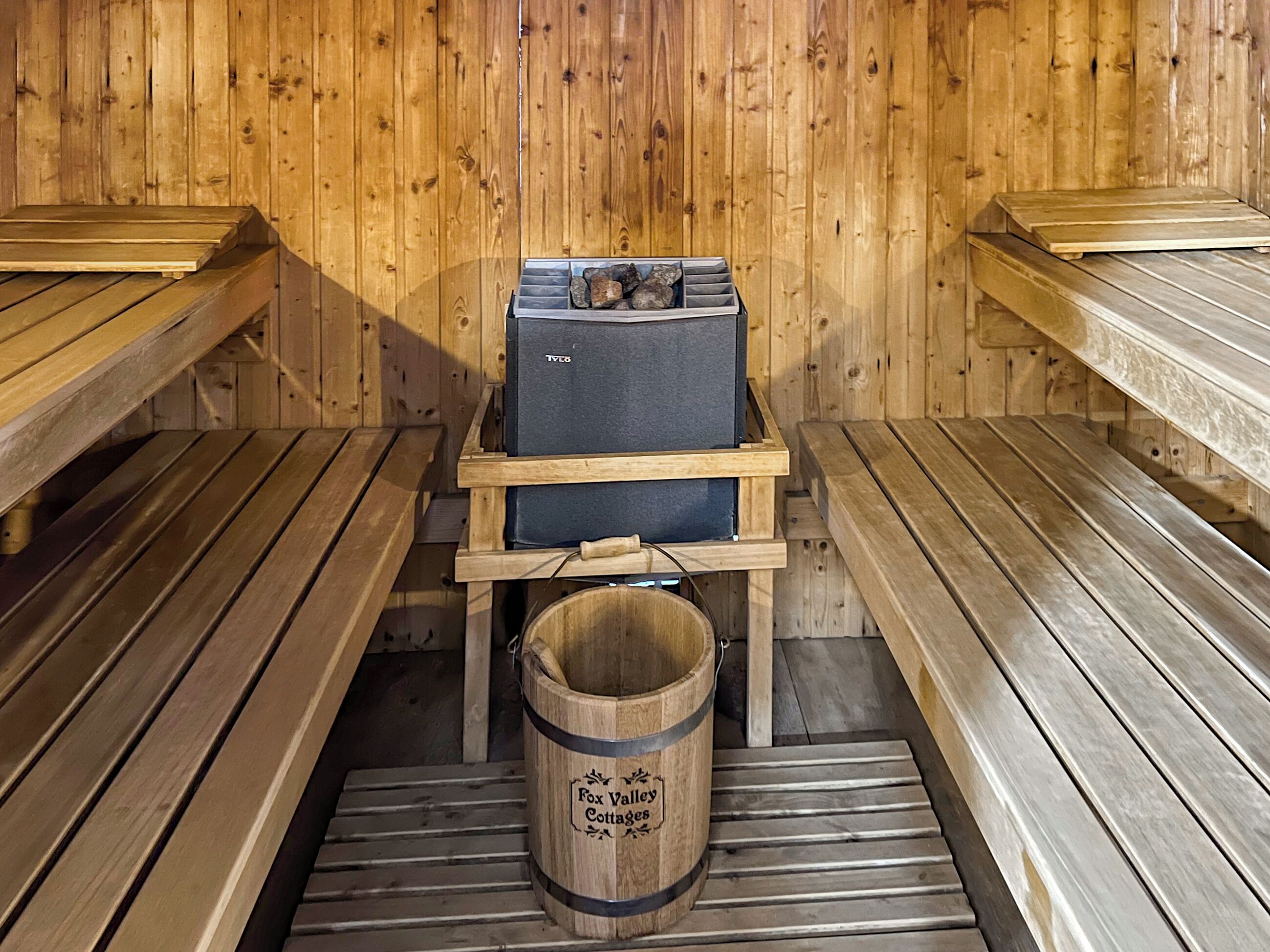 Uma sala de sauna com bancos de madeira e uma unidade de sauna identificada como 'TV8'.