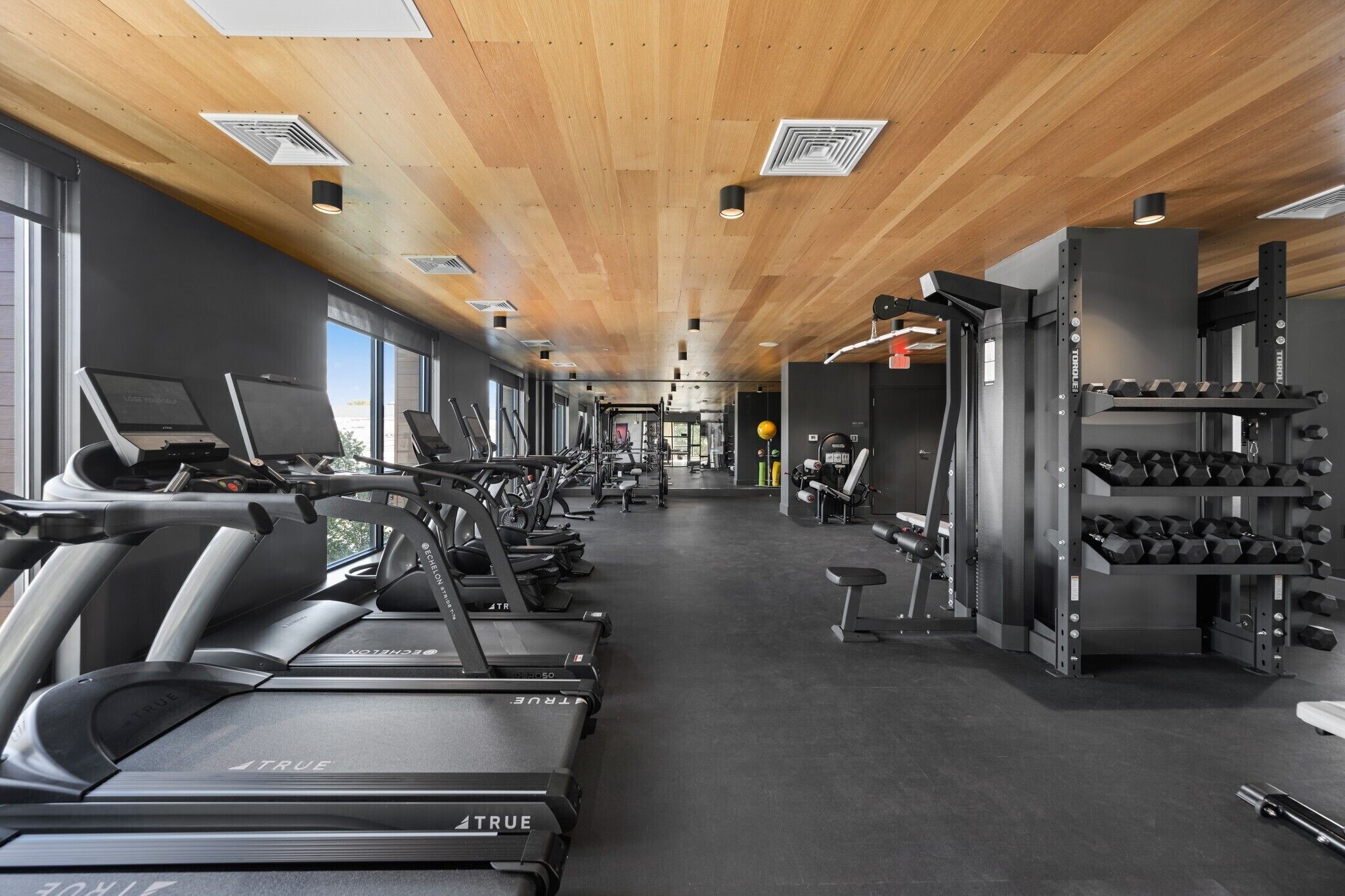 Et fitnesscenter med løbebånd, styrkemaskiner og håndvægte.