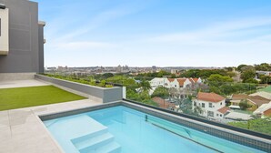Piscina no terraço com vista para a paisagem urbana e edifícios residenciais.