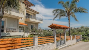 Un edificio de varios pisos con balcones, un muro de piedra y una valla de madera.
