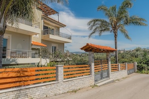 A multi-story building with balconies, a stone wall, and a wooden fence.