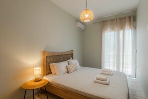 A bedroom with a bed, bedside lamp, and a hanging light fixture. - Aria Guest Residence, Apartment (Galatas)