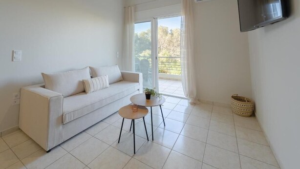 A modern living room with a sofa, a small round table, and a TV mounted on the wall.