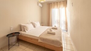 A minimalist bedroom with a single bed, a small bedside table, and a window with curtains.