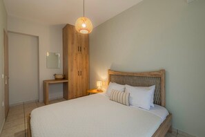 A bedroom with a wooden bed, a nightstand, a lamp, a wooden wardrobe, and a hanging light fixture.